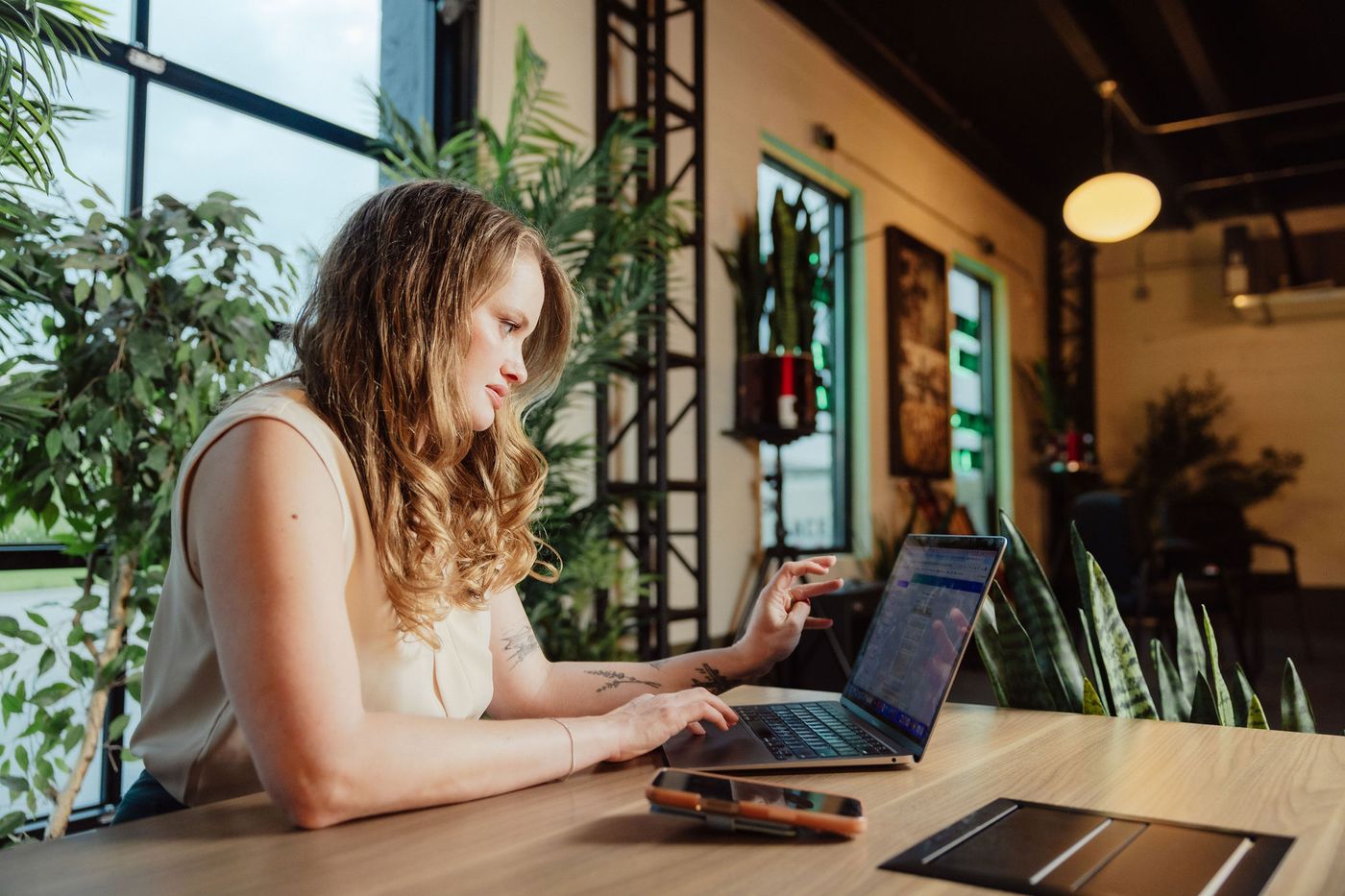 Lauren working at a laptop in a plant-filled workspace